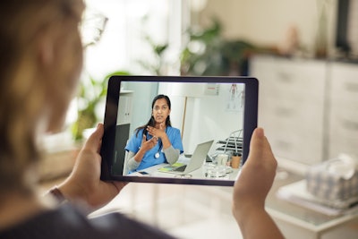 Person connecting with a female doctor online via a tablet.