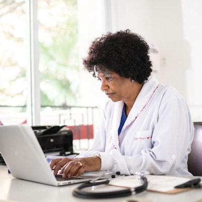 Female doctor working on a laptop computer.
