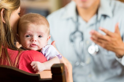 Mother holding baby with cystic fibrosis during pediatric appointment.