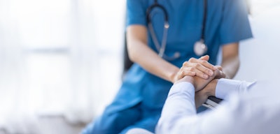 Nurse holding patients' hand in hospital setting.