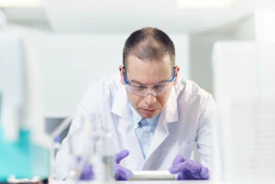 Image of scientist working in a laboratory setting, wearing safety goggles.