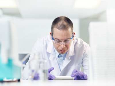 Image of scientist working in a laboratory setting, wearing safety goggles.