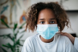 Portrait of a young African American little girl wearing a protective face mask.