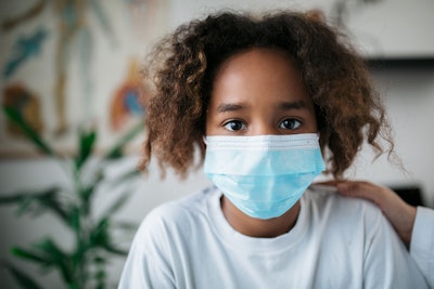 Portrait of a young African American little girl wearing a protective face mask.