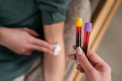 Female nurse holding blood collection tubes.