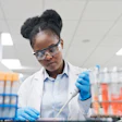 Young female scientist filling chemical through pipette while working in laboratory.