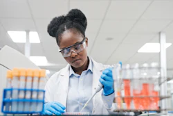 Young female scientist filling chemical through pipette while working in laboratory.