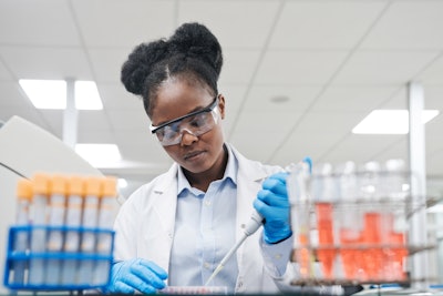 Young female scientist filling chemical through pipette while working in laboratory.