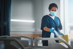 A Black, female nurse is cleaning a hospital bed.