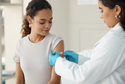 Shot of a young doctor applying a band-aid after injecting her patient during a consultation in the clinic.