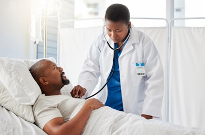 Medical doctor doing health checkup on patient in bed, and consulting black man after surgery at hospital.