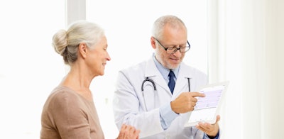 Photo of a male doctor showing a female patient data on a tablet.