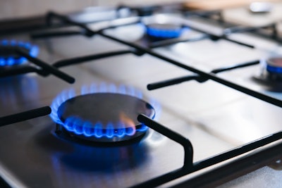 This photo is a closeup of several burners turned to a blue flame on a gas stove.