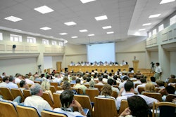 A panel of speakers is speaking to a large audience at a scientific conference.