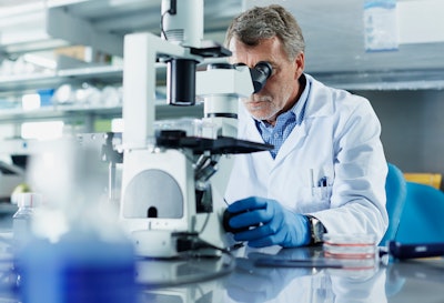 A scientist is using a microscope to conduct research in a lab.