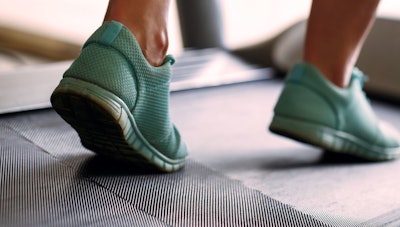 Photo of feet in running shoes on a treadmill.