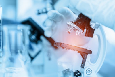 Close-up scientist using microscope in laboratory room while making medical testing and research.