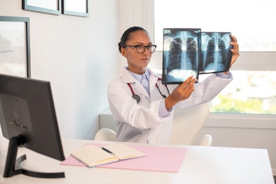 A female pulmonologist is reviewing lung x-rays.