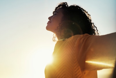 Woman outdoor at sunset during summer to relax with fresh air and sunshine.