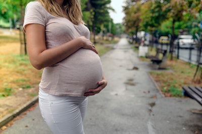 This is a photo of a pregnant woman in an urban setting, cradling her belly.