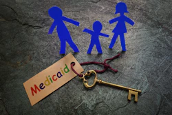 This picture shows a family of paper, stick figures next to a key labeled 'Medicaid.'