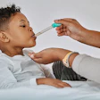 This is an image of a young, Black boy receiving an oral medicine via a syringe.