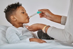 This is an image of a young, Black boy receiving an oral medicine via a syringe.