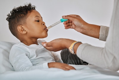 This is an image of a young, Black boy receiving an oral medicine via a syringe.