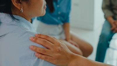 Woman with a comforting hand on her shoulder.