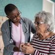 This is a photo of a nurse caring for an older woman in a senior center setting who looks confused.