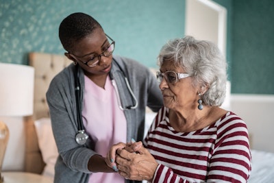 This is a photo of a nurse caring for an older woman in a senior center setting who looks confused.