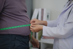 This is a photo of a medical professional measuring the diameter of a man's waist with measuring tape.