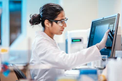 Female researcher in a lab setting working on a touch screen monitor