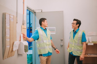 This is a photo of two Asian men clocking in at work.