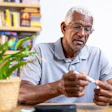 This is a photo of an older, Black man testing his blood sugar with a finger stick.