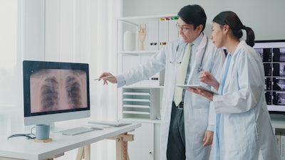 Image of a male and female doctor consulting over an x-ray of lungs.