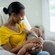 This is a photo of a young, Black woman breastfeeding her baby.