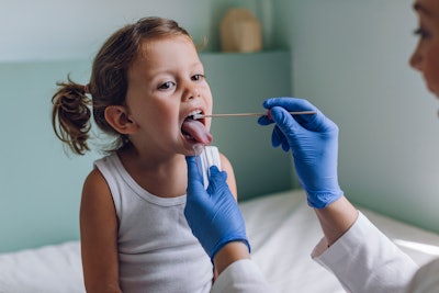 Nurse performing a mouth swab test on a young child in the hospital.
