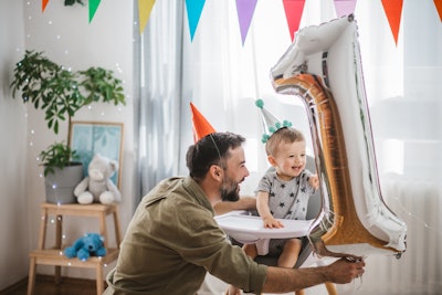 This is a photo of a dad and young child celebrating the child's first birthday.