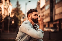 Image of a man in his 30s using an inhaler.