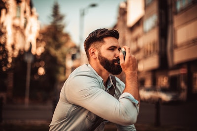 Image of a man in his 30s using an inhaler.
