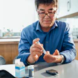 This is a photo of an Asian man pricking his finger to test his blood sugar for diabetes.