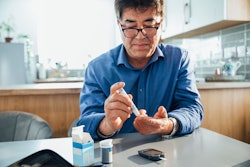 This is a photo of an Asian man pricking his finger to test his blood sugar for diabetes.