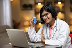 Female Indian American doctor holds inhaler during virtual appointment on a laptop.