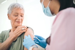Health care worker gives vaccine to older woman.