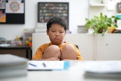 This is a photo of an elementary-aged Asian boy having trouble focusing in school.
