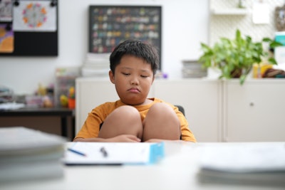 This is a photo of an elementary-aged Asian boy having trouble focusing in school.