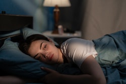 This is a photo of a young, white woman lying awake in bed with insomnia.