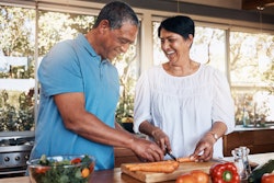 Mature man and woman cooking healthy meal in kitchen.