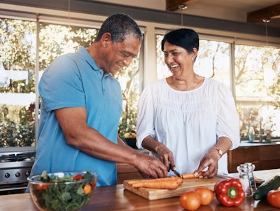 Mature man and woman cooking healthy meal in kitchen.